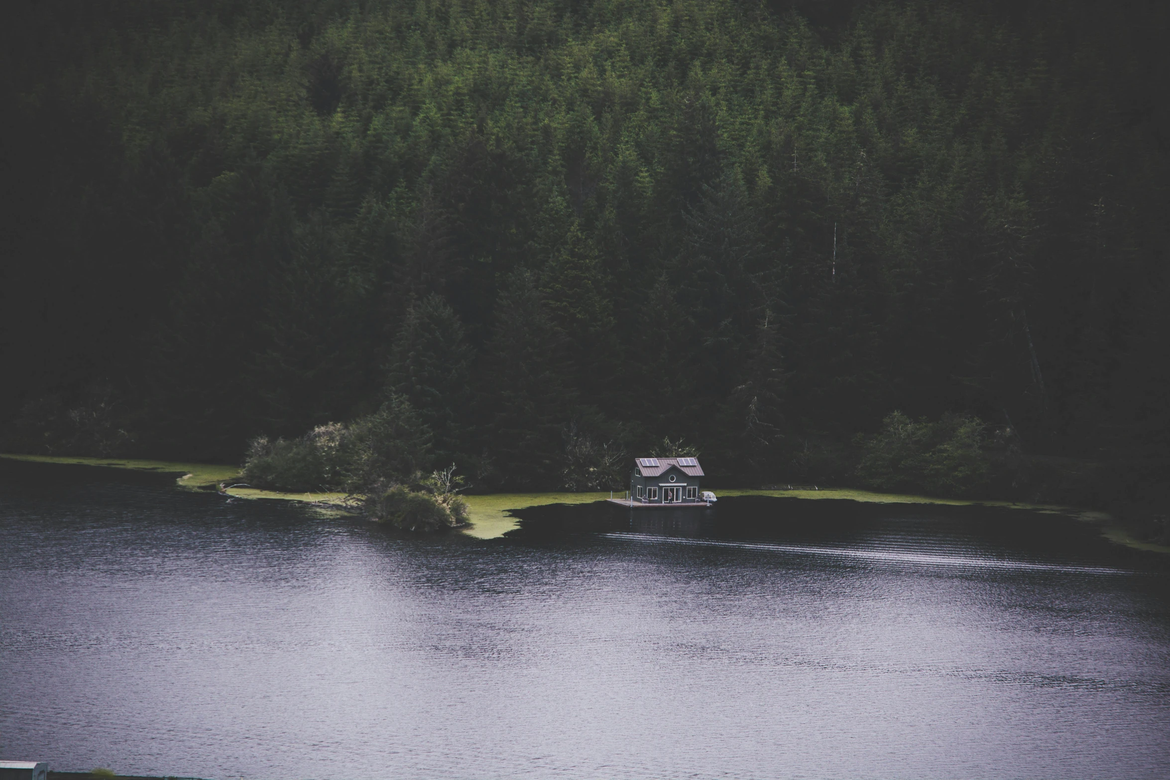 a boat sitting on top of a lake next to a forest, by Karl Buesgen, pexels contest winner, hurufiyya, location of a dark old house, haida gwaii, lo-fi, cabin