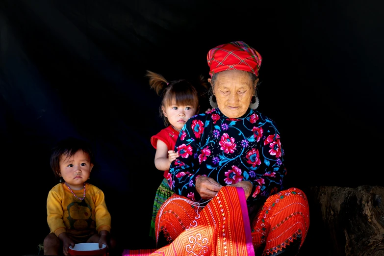 a woman and two children sitting next to each other, a portrait, pexels contest winner, phuoc quan, tribal clothing, portrait image, an elderly