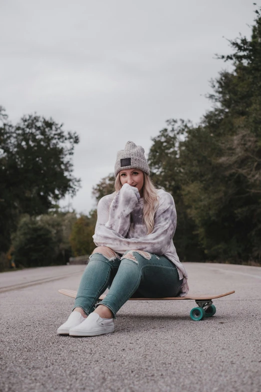 a woman sitting on a skateboard in the middle of the road, trending on pexels, grey sweater, teal, sitting in a tree, high quality photo