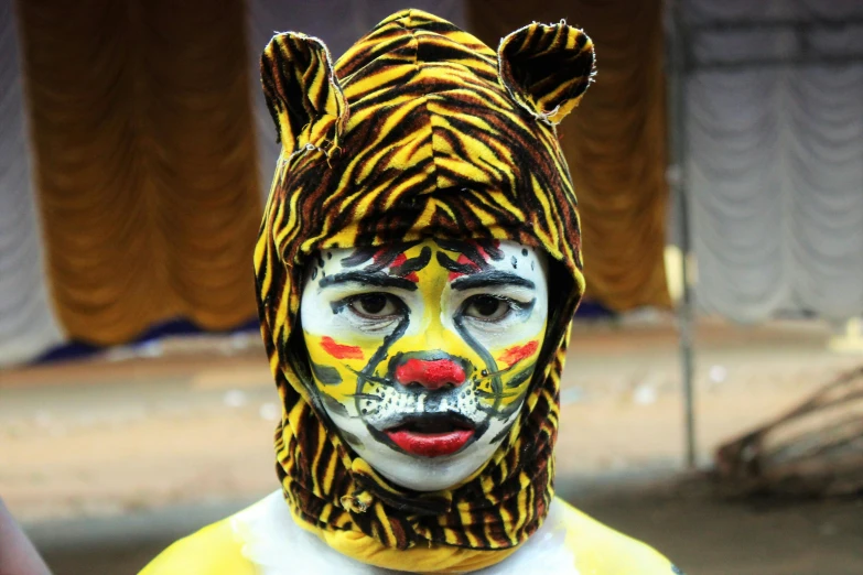 a close up of a person wearing a tiger mask, an album cover, by Sudip Roy, bengal school of art, circus performance, little kid, yellow makeup, football mascot