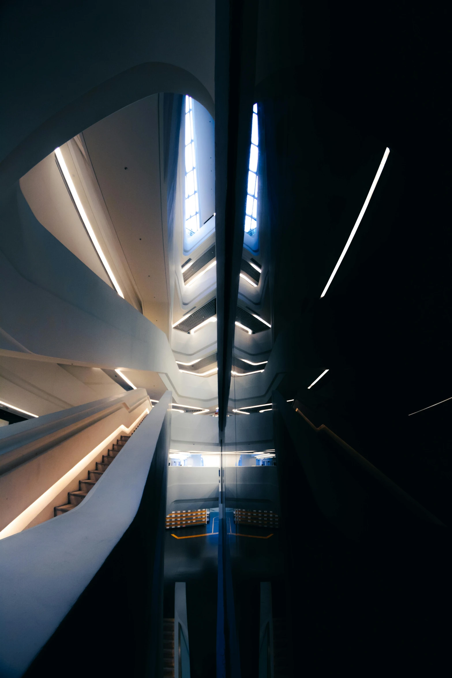 a train traveling through a train station at night, an abstract sculpture, inspired by Zaha Hadid, unsplash contest winner, light and space, narrow hallway, high angle vertical, interior of a star destroyer, lower and upper levels