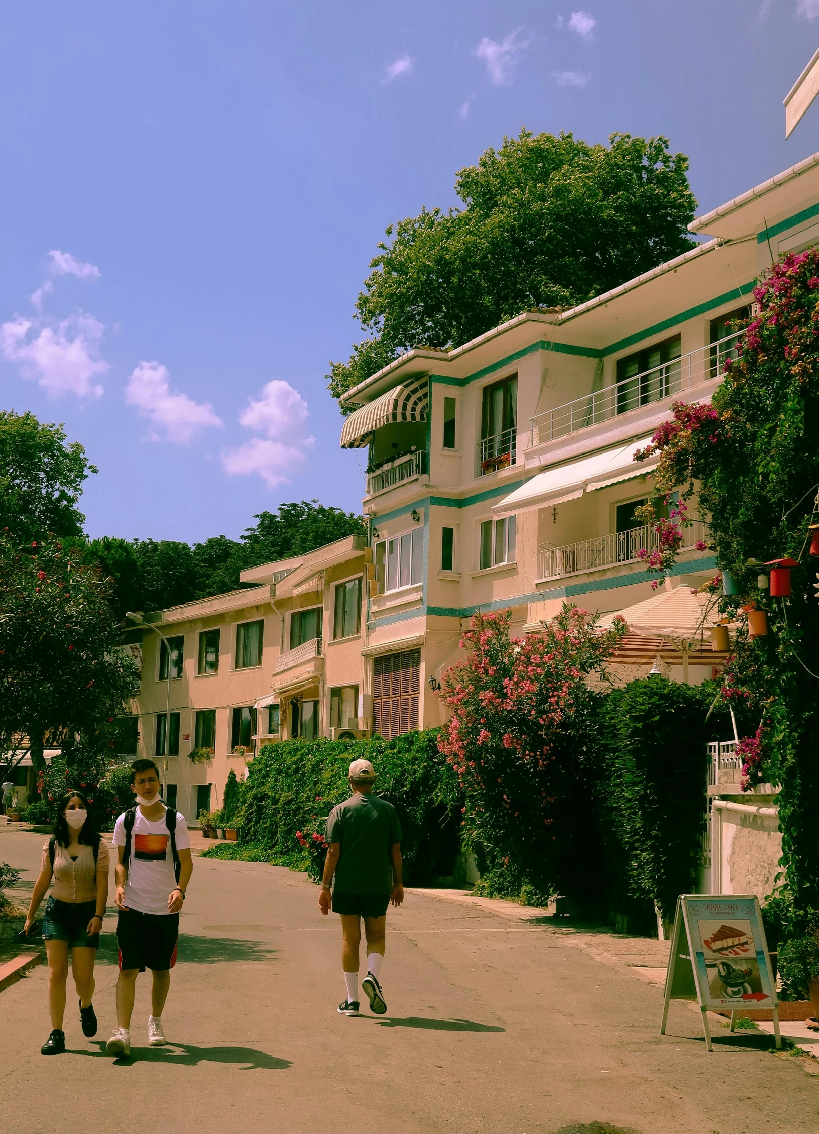 a group of people walking down a street, a colorized photo, inspired by Ricardo Bofill, instagram, danube school, rich greenery, seaside, [ cinematic, full building