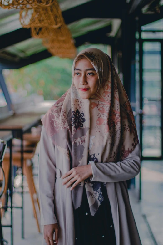 a woman wearing a hijab standing in a restaurant, inspired by Nazmi Ziya Güran, unsplash contest winner, hurufiyya, patterned scarf, brown, grey, indonesia