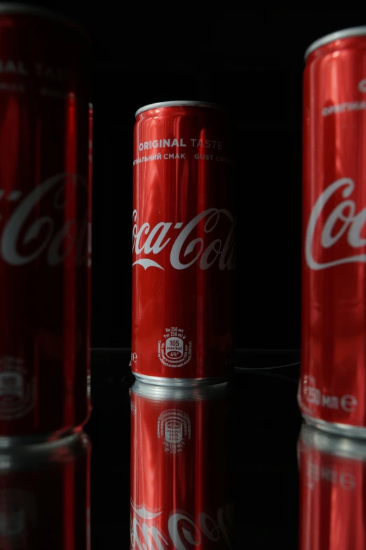 a group of coke cans sitting on top of a table, standing with a black background, shot on sony a 7, reds, drink