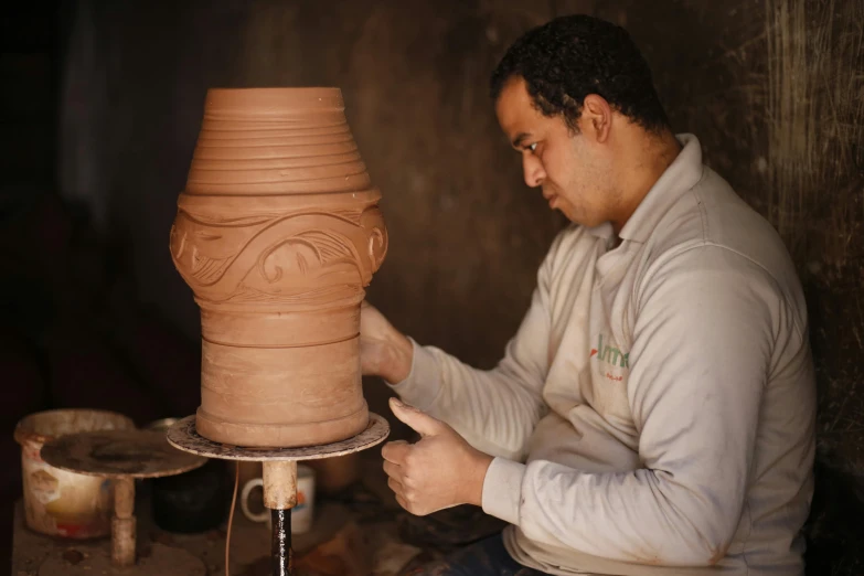 a man is making a vase out of clay, an album cover, by Riad Beyrouti, pexels contest winner, detailed carved ornaments, thumbnail, portrait of tall, crisp smooth lines