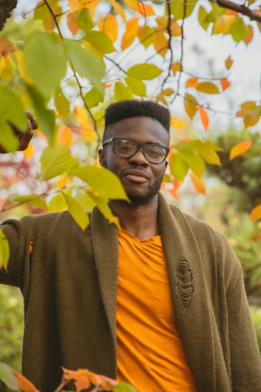 a man wearing glasses standing next to a tree, by Stokely Webster, during autumn, jaylen brown, yellow hue, square rimmed glasses