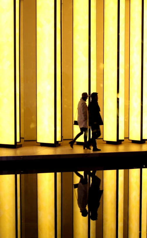 a couple standing next to each other in front of a building, inspired by Ryoji Ikeda, flickr, yellow lanterns, inside a tall vetical room, photograph credit: ap, people walking