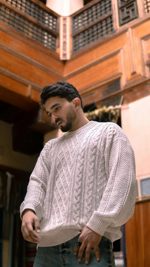a man in a white sweater standing in a room, pexels, in egypt, made of wool, streetwear, thumbnail