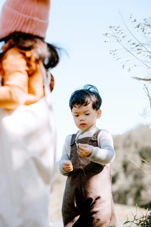 a little boy that is standing in the grass, pexels contest winner, symbolism, looking her shoulder, asian man, motherly, overalls