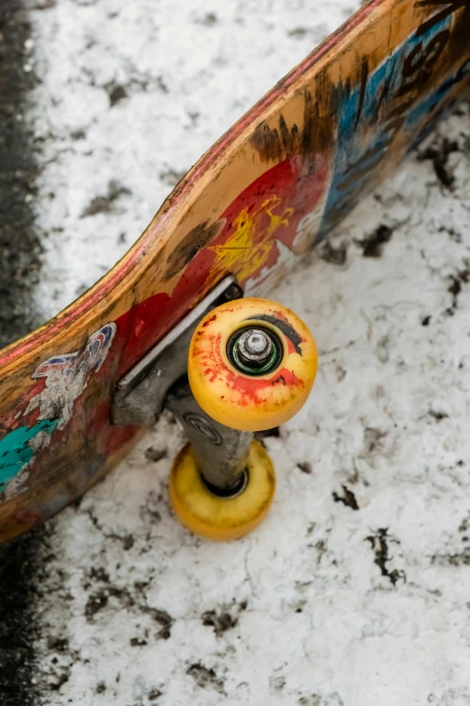 a skateboard that is sitting in the snow, by Doug Ohlson, trending on unsplash, graffiti, faded red and yelow, knobs, multicolored, high angle close up shot