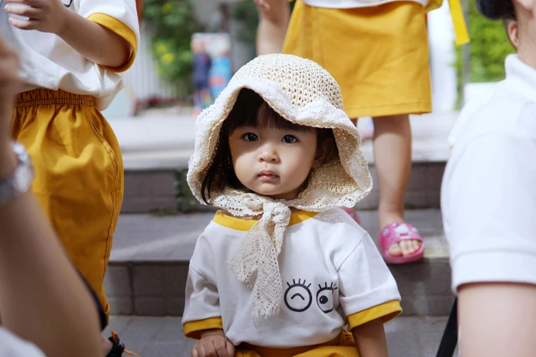 a close up of a child wearing a hat, inspired by Nara Yoshitomo, pexels contest winner, white and yellow scheme, in style of lam manh, square, school class