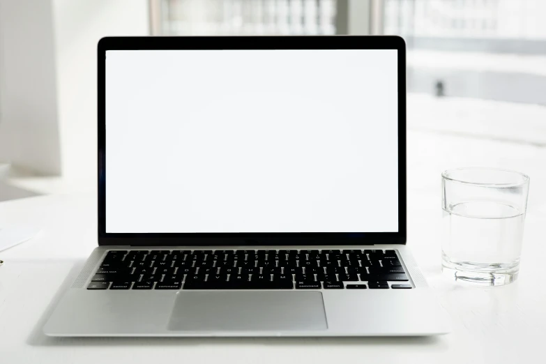 a laptop computer sitting on top of a desk next to a glass of water, pexels, white space, rectangle, white, displayed