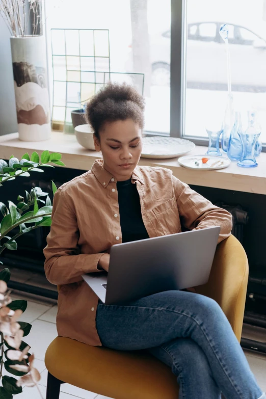 a woman sitting in a chair with a laptop, pexels contest winner, short blonde afro, thumbnail, mixed-race woman, concentration