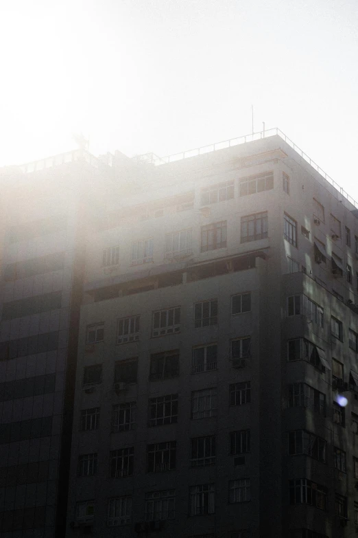 a tall building sitting in the middle of a city, by Youssef Howayek, light and space, sunflares;back to camera, :: morning, talaat harb square cairo, bladerunner apartment