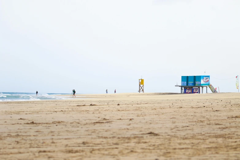 a group of people standing on top of a sandy beach, by Eglon van der Neer, unsplash, minimalism, square, huts, gold coast australia, viewed from a distance