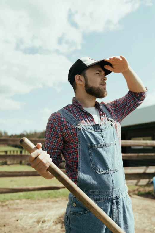 a man in overalls standing in front of a barn, by Jessie Algie, pexels contest winner, looking confused, holding a baseball bat, farming, lachlan bailey