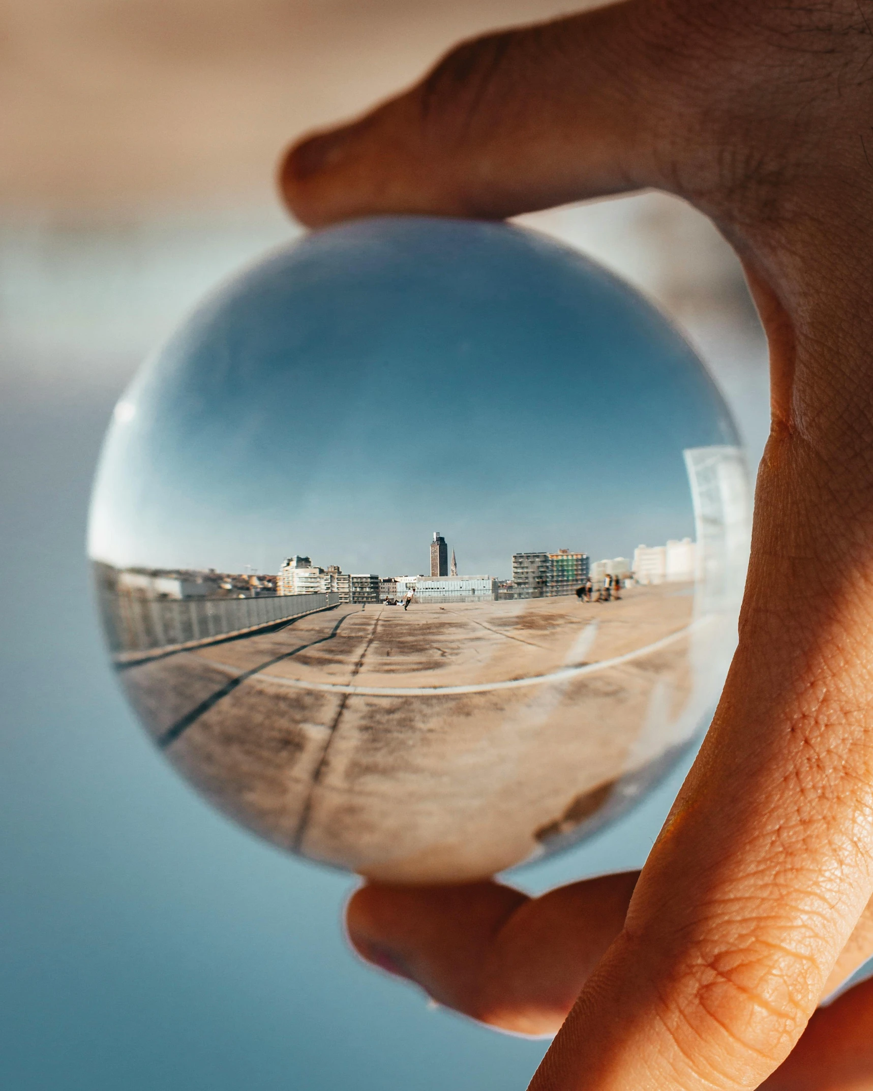 a person holding a crystal ball in their hand, by Christen Dalsgaard, unsplash contest winner, super wide view of a cityscape, in a beachfront environment, overexposed photograph, hdri