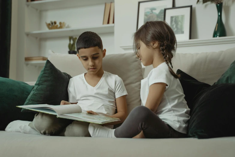 two children sitting on a couch reading a book, a cartoon, by Adam Marczyński, pexels contest winner, happening, gif, looking sideways, maintenance, profile pic