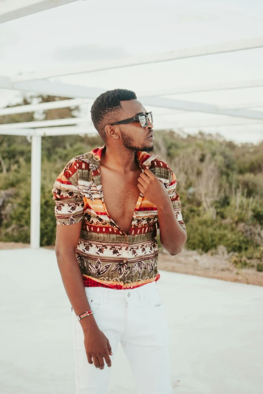 a man in a colorful shirt and white pants, inspired by Theo Constanté, trending on pexels, with brown skin, looking heckin cool and stylish, in africa, open v chest clothes