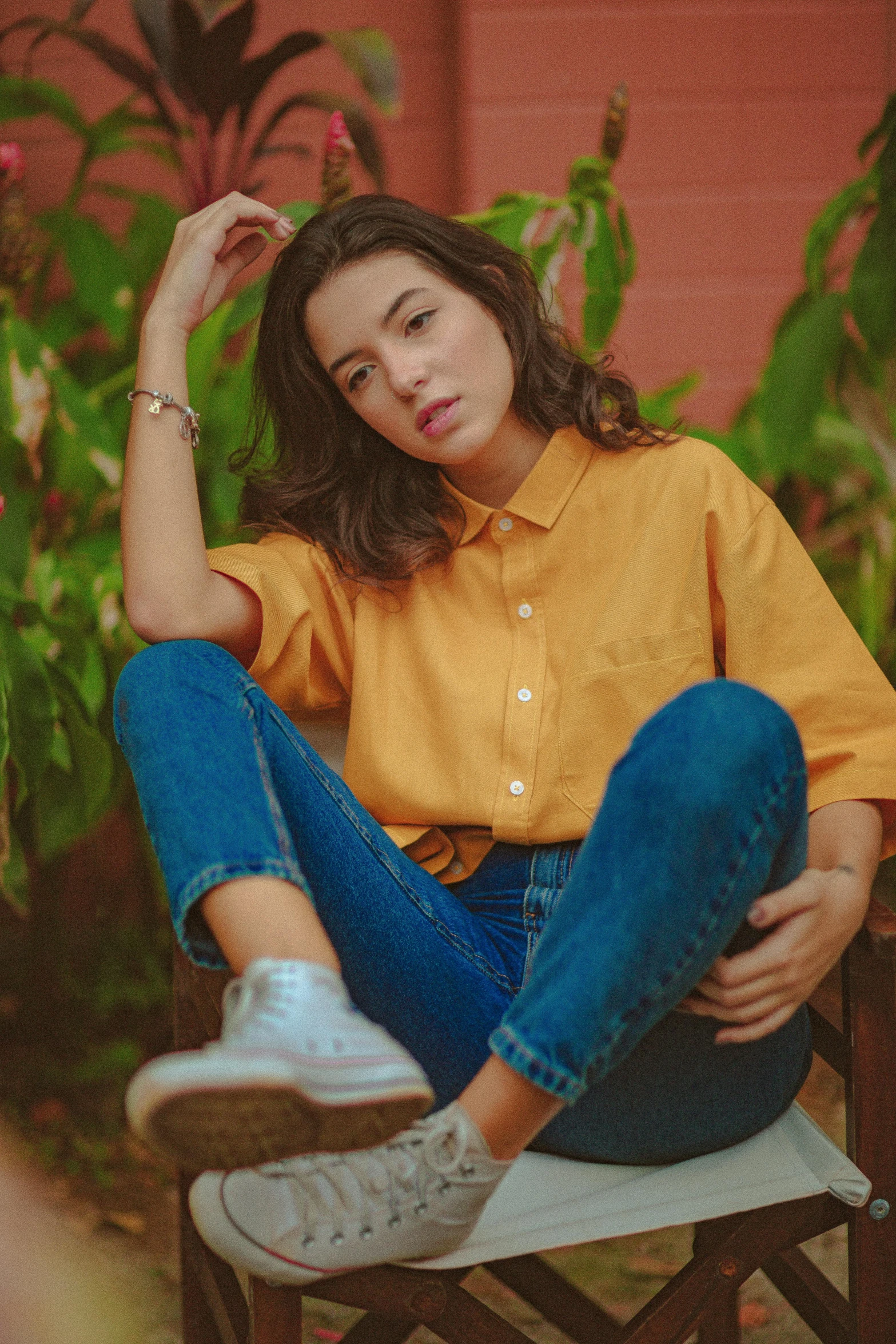 a woman sitting on top of a wooden chair, inspired by Elsa Bleda, trending on pexels, wearing a modern yellow tshirt, collared shirt, asian girl, ( ( ( wearing jeans ) ) )