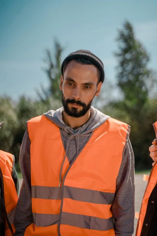 a group of men standing next to each other, by David Begbie, pexels contest winner, hurufiyya, salma hayek in a hi vis vest, bearded, orange pupils, reflective material