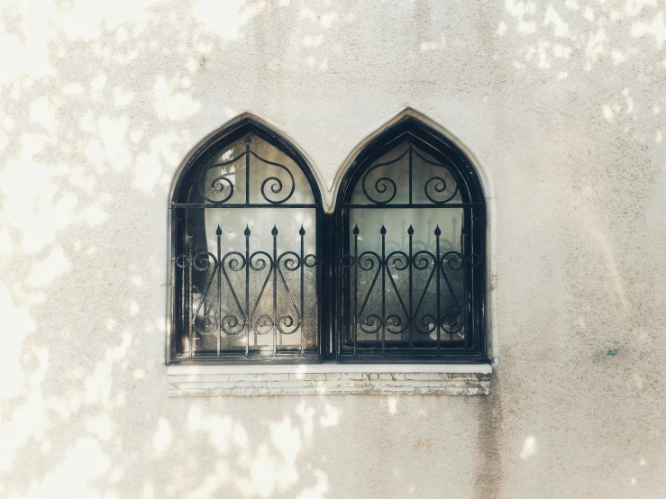 a couple of windows sitting on the side of a building, pexels contest winner, arabesque, filtered light, gothic arch frame, trending on vsco, wrought iron