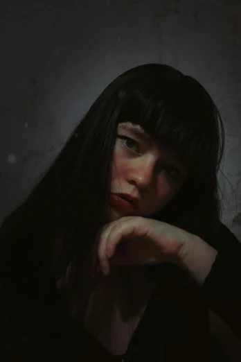 a woman sitting in a dark room with her hand on her chin, an album cover, pexels contest winner, realism, hair blackbangs hair, very pale skin, dark. no text, ((portrait))