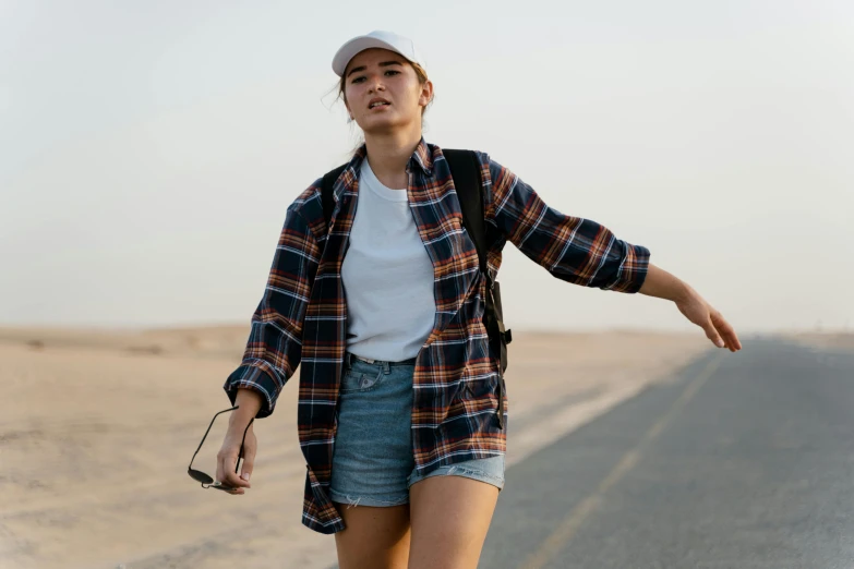 a woman riding a skateboard down the middle of a road, trending on pexels, happening, standing in desert, wearing a flannel shirt, asian women, mid 2 0's female