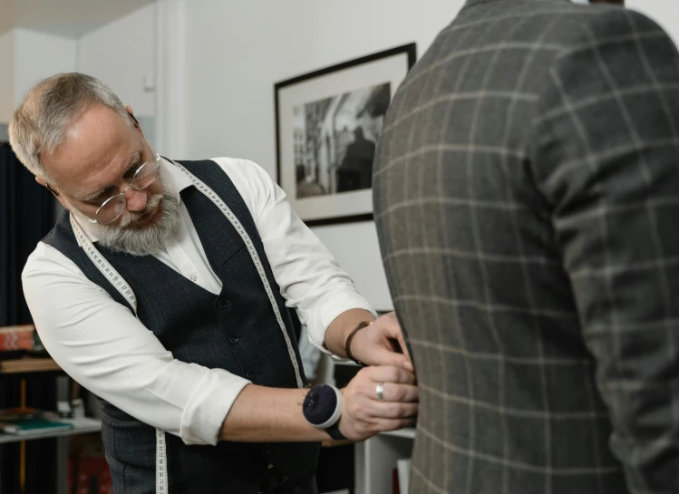 a man standing next to another man in a room, inspired by Constantin Hansen, pexels contest winner, old wool suit, measurements, insisted on cutting in line, shot from the back