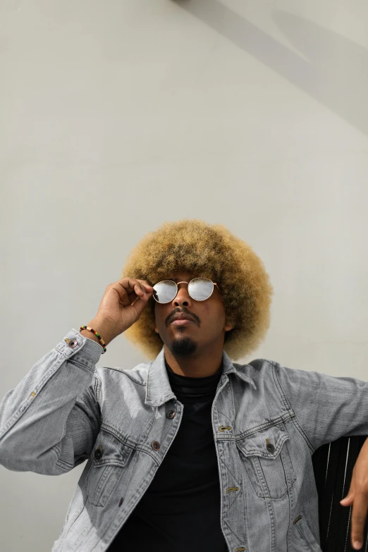 a man sitting in a chair talking on a cell phone, an album cover, by Afewerk Tekle, trending on unsplash, afrofuturism, curly blond hair, aviators, with afro, confident pose
