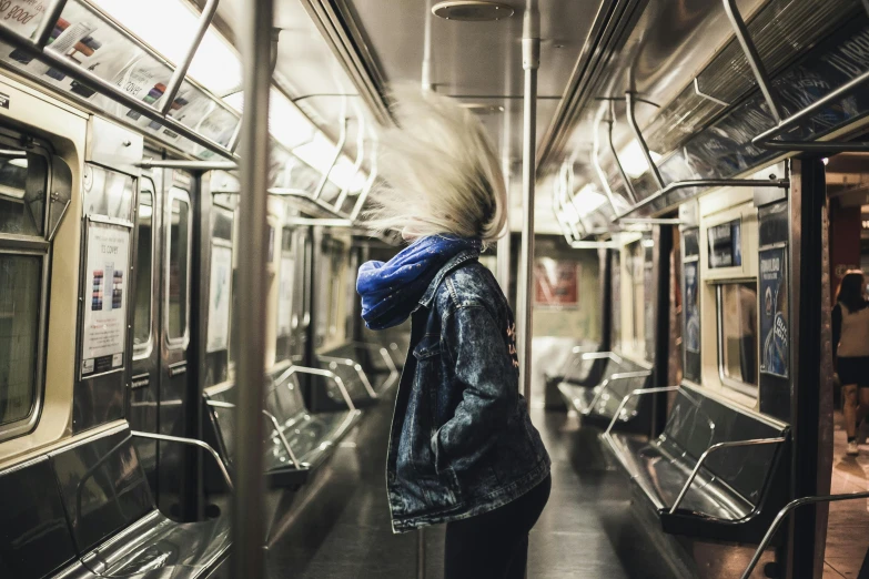 a person standing inside of a subway car, by Emma Andijewska, unsplash contest winner, her hair blowing in the wind, in the middle of new york, face covered, instagram post