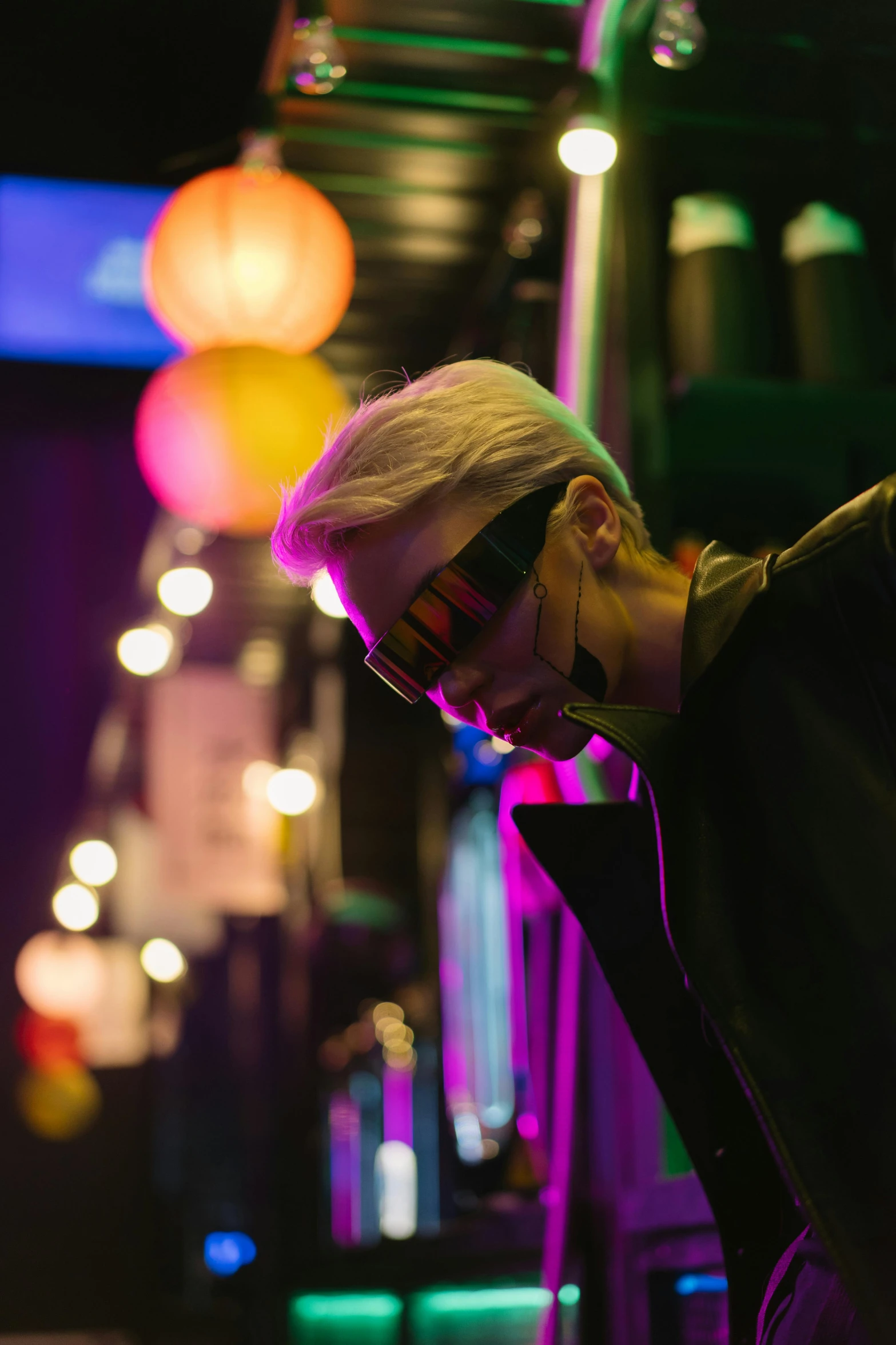 a close up of a person on a cell phone, cyberpunk art, trending on pexels, a 1980s goth nightclub in soho, futuristic sunglasses, blonde man, contemplating