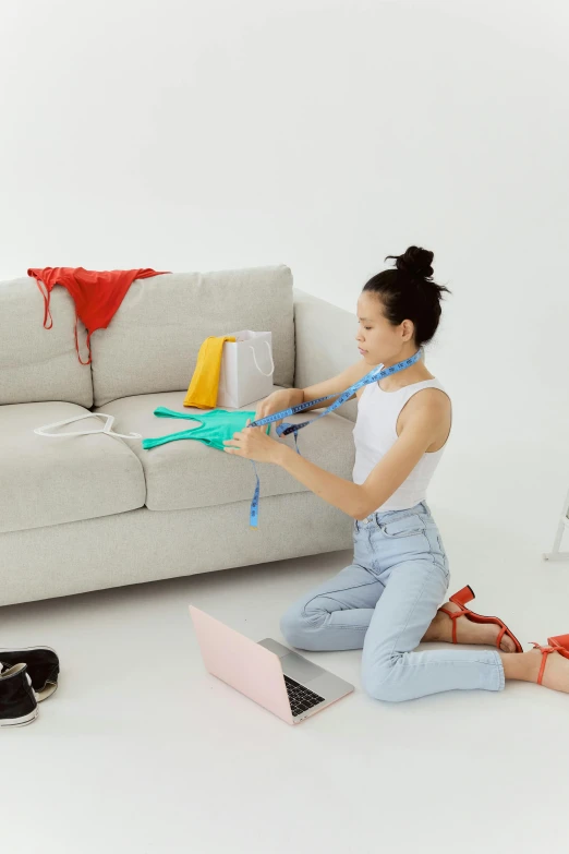 a woman sitting on the floor in front of a couch, clothing drop, measurements, with a bunch of stuff, profile image