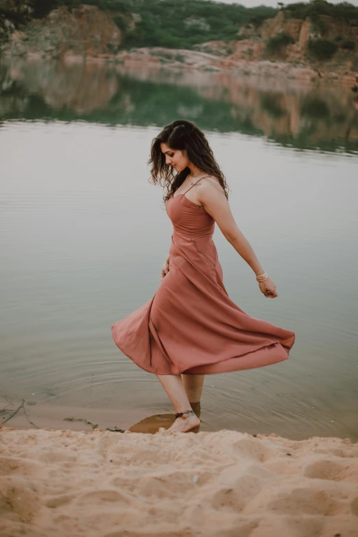 a woman standing on a beach next to a body of water, pink dress, she is walking on a river, in a dusty red desert, satisfied pose
