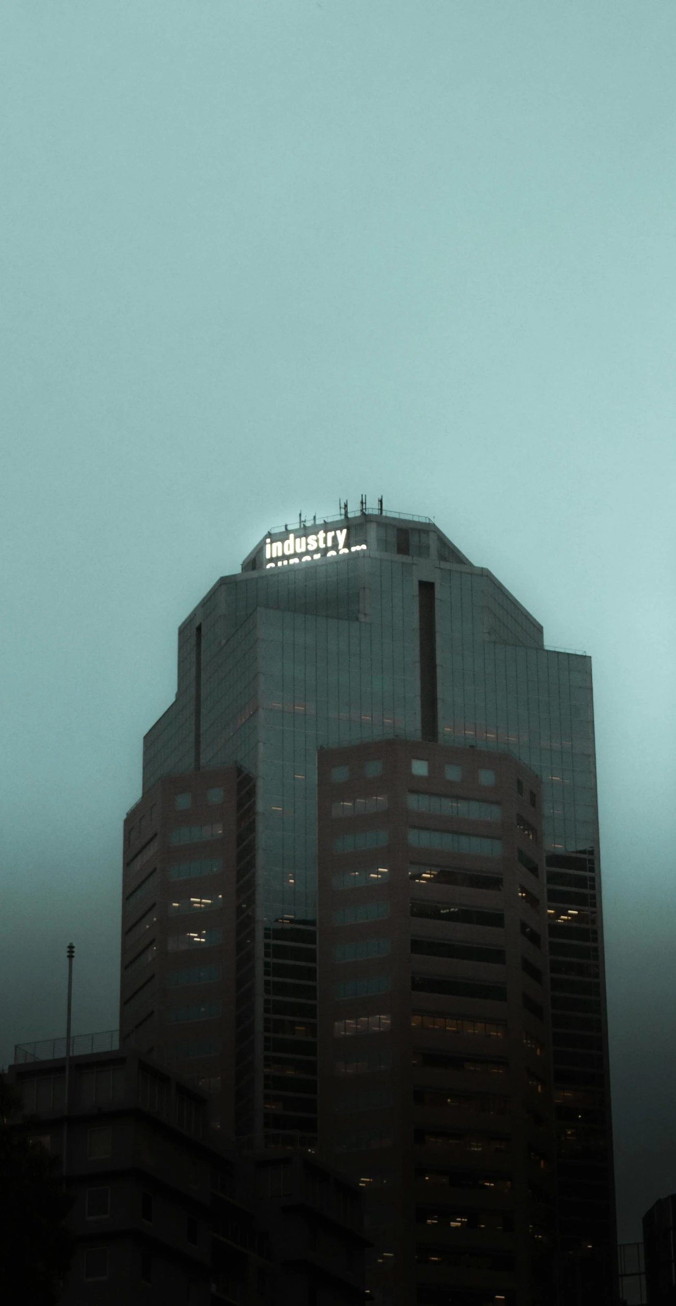 a very tall building sitting in the middle of a city, by Robert J. Brawley, moody hazy lighting, billboard image