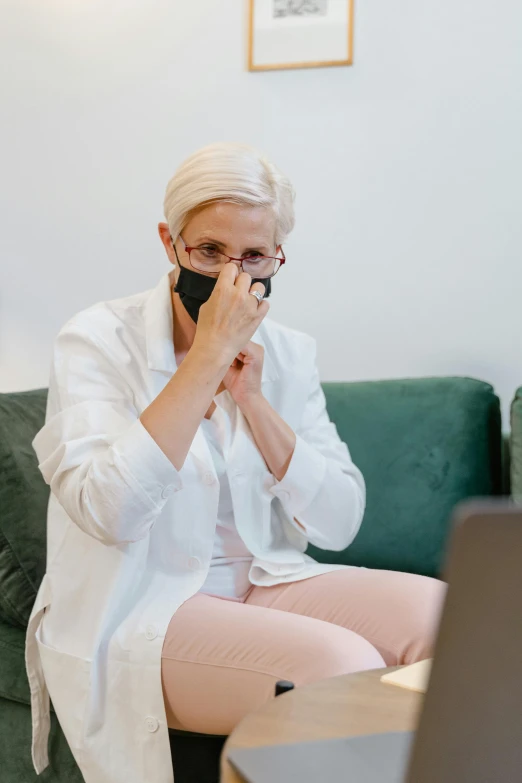 a woman sitting on a couch in front of a laptop, surgical mask covering mouth, white haired lady, people crying, barbara canepa