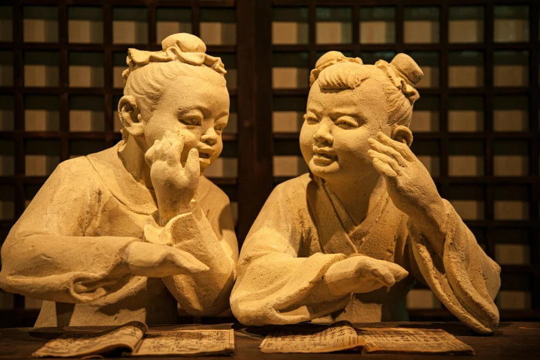 a couple of statues sitting on top of a wooden table, a marble sculpture, inspired by Zhang Shunzi, mingei, kids, museum, highlight, japanese facial features