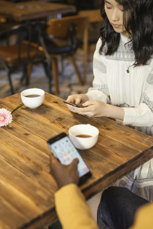 a couple of people that are sitting at a table, trending on pexels, happening, goddess checking her phone, sitting on a mocha-colored table, japanese, square