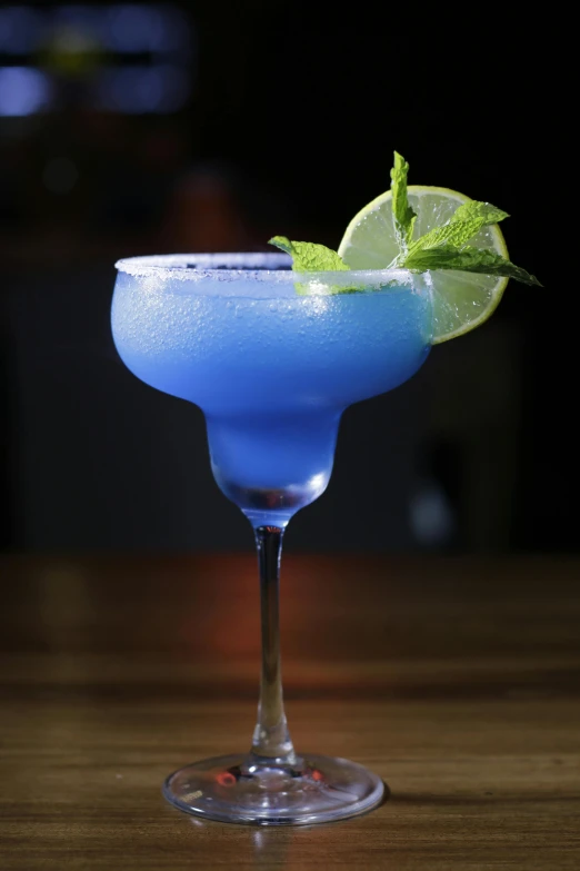 a blue cocktail sitting on top of a wooden table