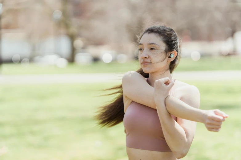 a woman in a pink sports bra top standing in a park, trending on pexels, renaissance, waist reaching ponytail, ryan jia, strong wind, full frame image