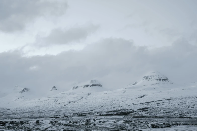 a black and white photo of a snow covered mountain, by Hallsteinn Sigurðsson, pexels contest winner, hurufiyya, three towers, muted cold colors, (3 are winter, viewed from a distance