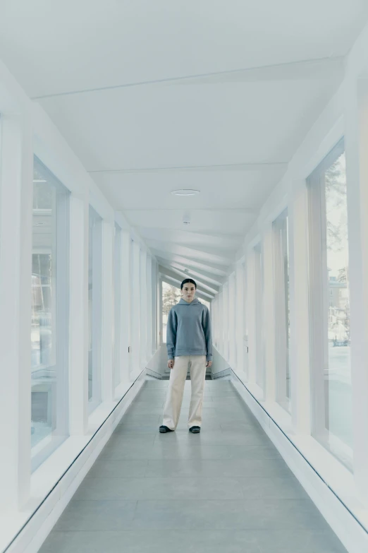 a man is walking down a long hallway, inspired by Fei Danxu, light and space, soft cool colors, promo image, he is at college, white sky