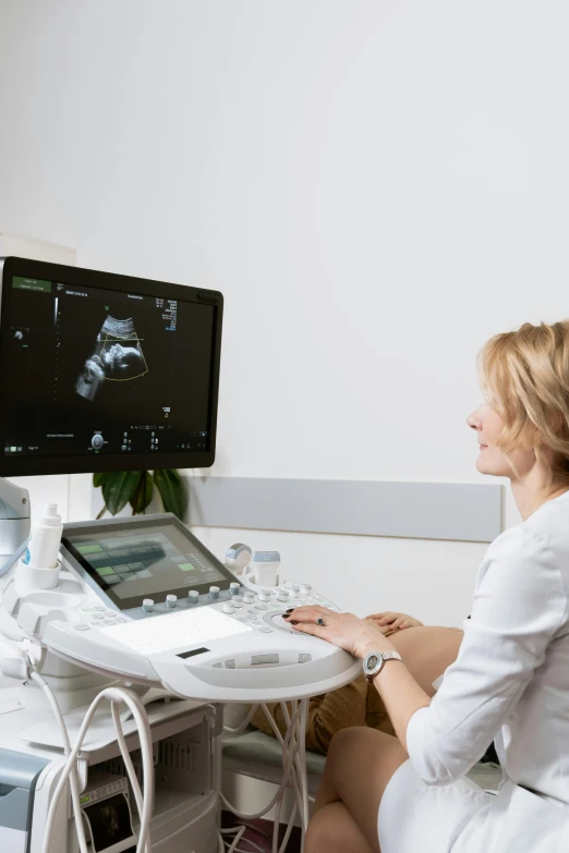 a woman sitting at a desk in front of a computer, membrane pregnancy sac, ultradetails, very consistent, colour photograph