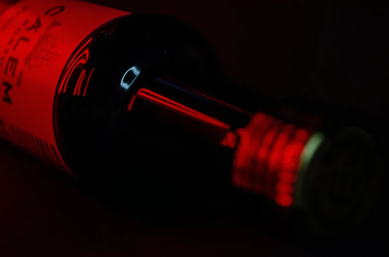 a bottle of wine sitting on top of a table, pexels contest winner, conceptual art, volumetric lighting. red, red neon, close up details, detailed product image