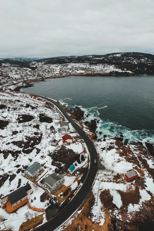 a road next to a body of water covered in snow, by Jesper Knudsen, pexels contest winner, flooded fishing village, wide high angle view, views to the ocean, sparkling cove