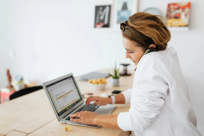 a woman sitting at a table using a laptop computer, trending on pexels, wearing lab coat and a blouse, profile image, wearing headset, wotjek fus