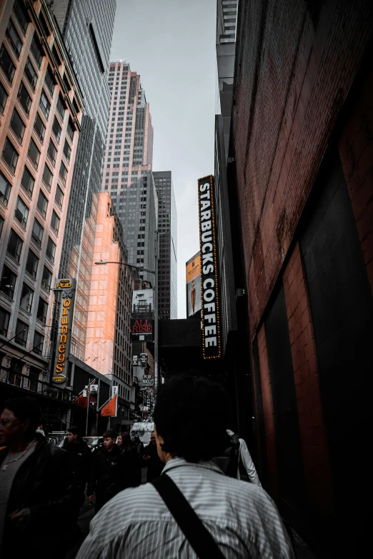 a crowd of people walking down a street next to tall buildings, a picture, pexels contest winner, starbucks, background image, broadway, # glazersout