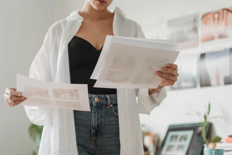 a woman holding two sheets of paper in her hands, a photocopy, by Emma Andijewska, pexels contest winner, lab coat and tee shirt, wearing a sexy cropped top, on a canva, multiple stories