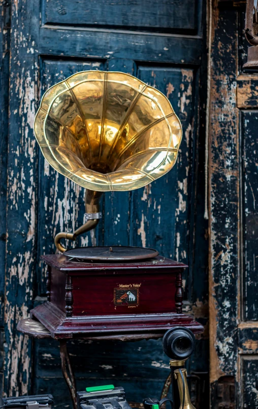 a gramphone sitting on top of a table next to a door, trending on pexels, assemblage, brown and gold, high quality photo, head shot, lights on