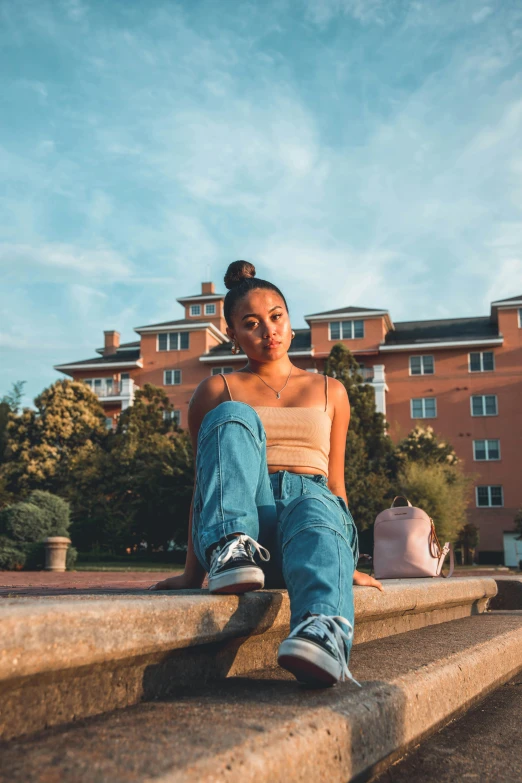 a woman sitting on the steps of a building, doja cat, with a park in the background, baggy jeans, portrait featured on unsplash